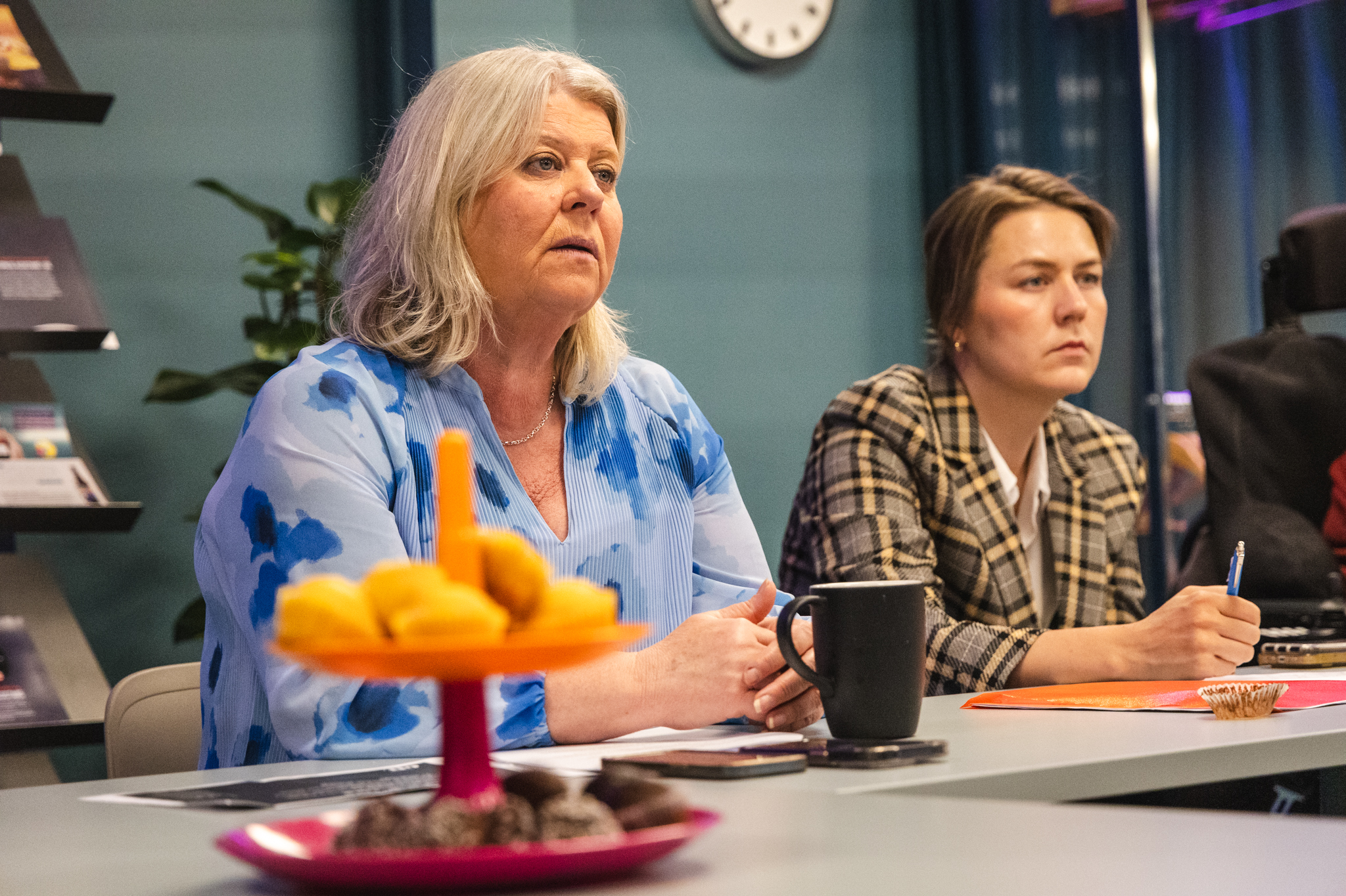 Camilla Waltersson Grönvall samt Victoria Seeman vid konferensbord, fika i förgrunden, allvarliga blickar.